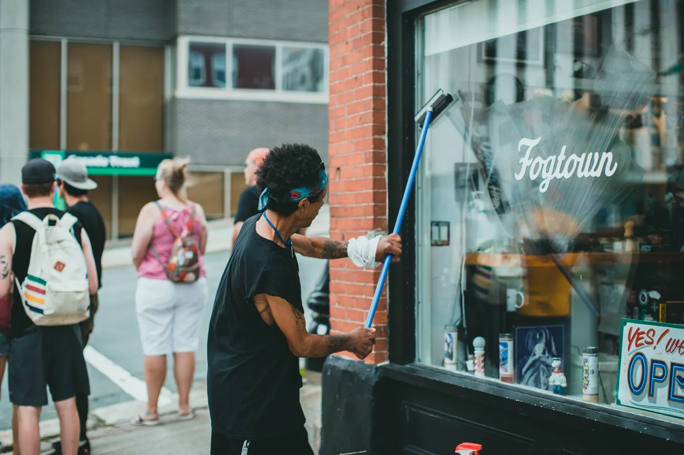 Nettoyage de la vitrine d'un commerce à la raclette, depuis le trottoir